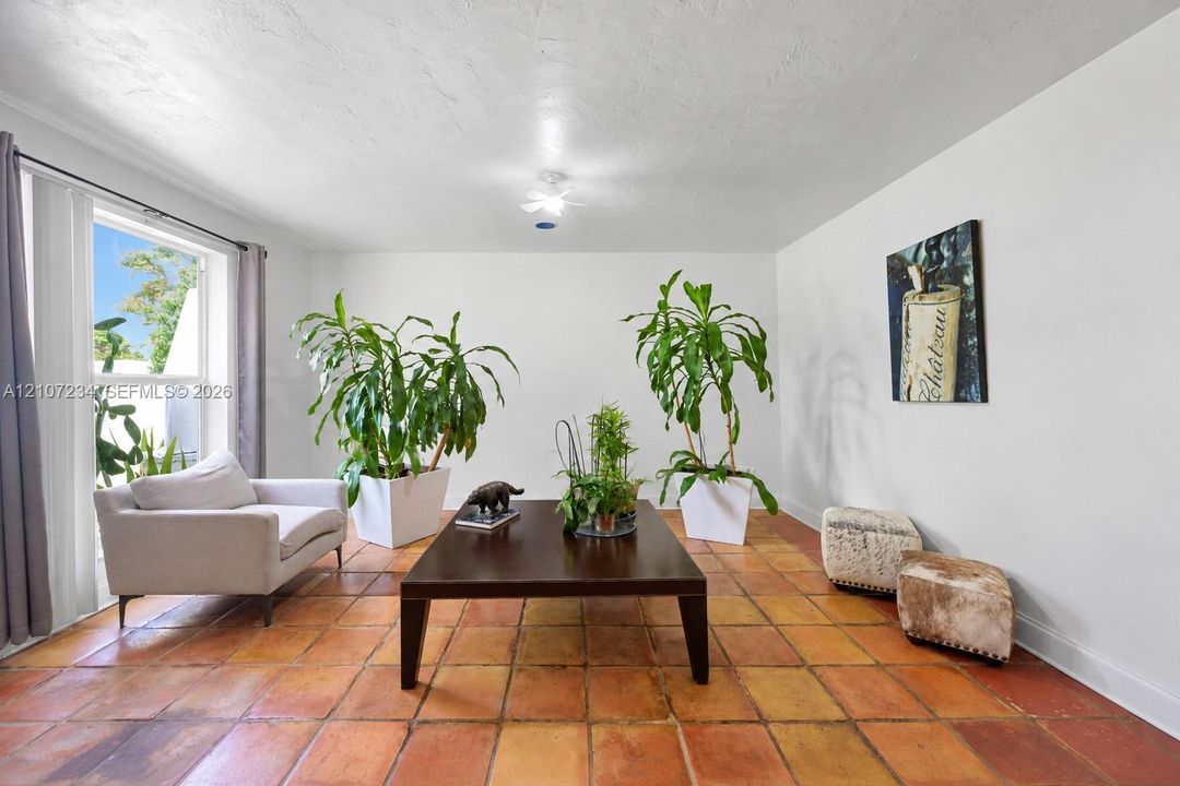 Interior space featuring large-format terra cotta tile flooring, expansive window with natural lighting, and ceiling-mounted light fixture