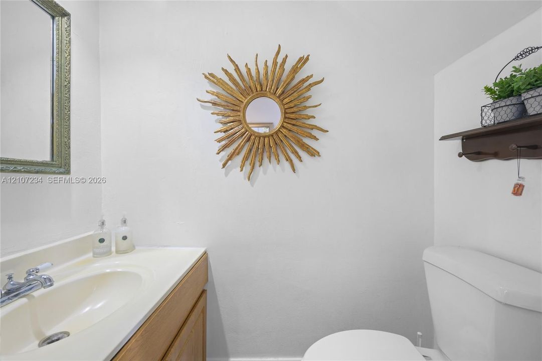 Wood-finish vanity featuring an integrated basin and a chrome-finish faucet, complemented by a wall-mounted wooden shelf