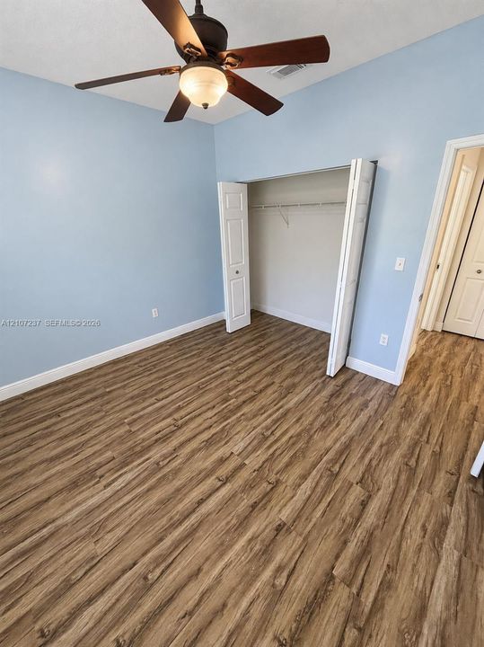 Room featuring wood-finish flooring, a ceiling fan with integrated light, and a closet with bifold doors
