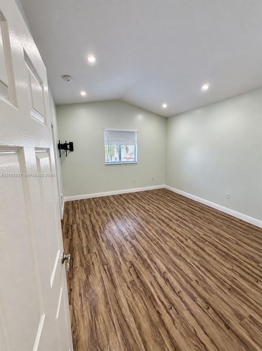 Vaulted ceilings featuring recessed lighting, wood-finish flooring, and a single window