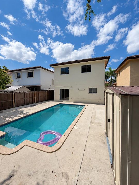Rectangular swimming pool with tiled coping, expansive concrete pool deck, and perimeter wood privacy fencing