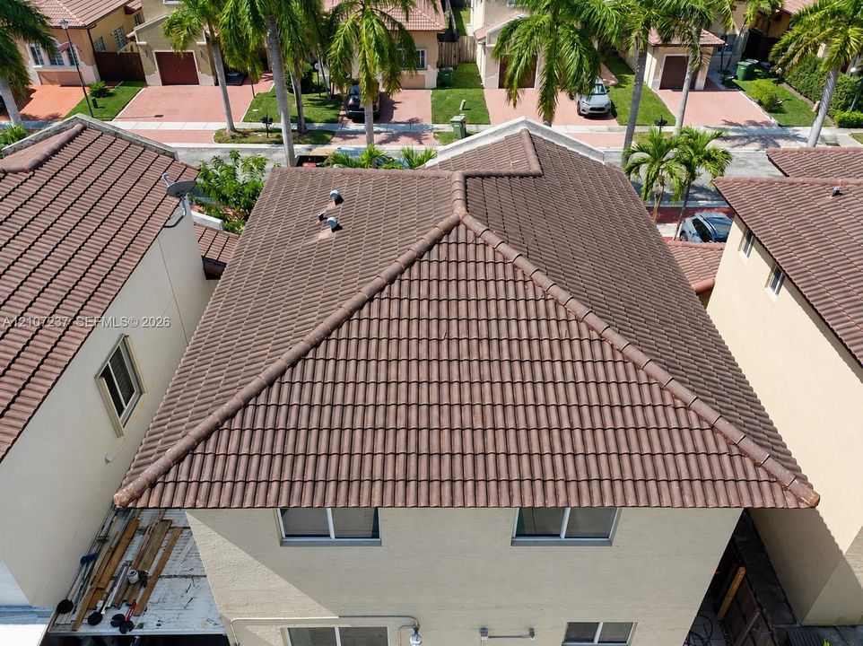 Multi-level residence featuring a hipped roof with textured tile finish and light-toned stucco exterior walls