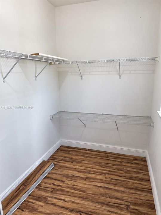 Storage area featuring wood-finish flooring and multi-level wall-mounted wire shelving