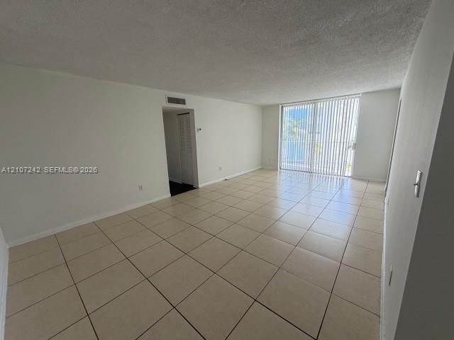 Spacious interior featuring neutral ceramic tile flooring, sliding glass doors, and a textured ceiling finish