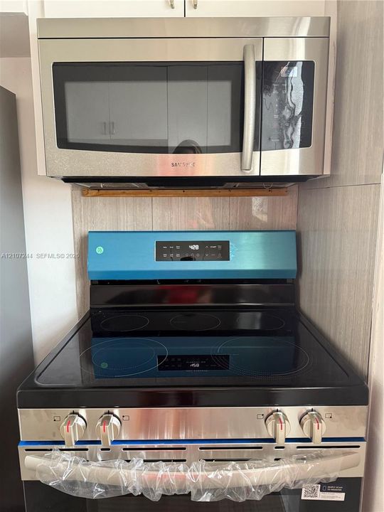 Stainless steel over-the-range microwave and electric range with a smooth-top glass cooktop and tile backsplash