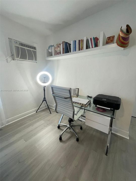 Wood-finish flooring, white wall-mounted shelving, and wall-mounted air conditioning unit