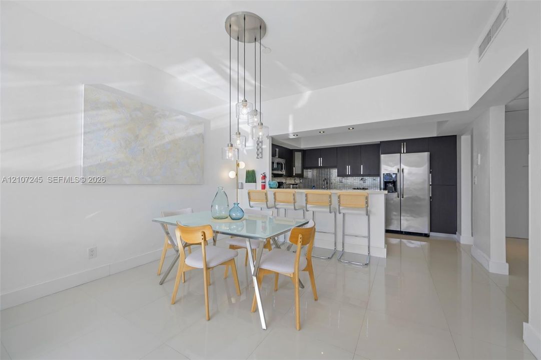 Kitchen featuring dark cabinetry, stainless steel appliances, breakfast bar, and multi-light pendant fixture over tile flooring