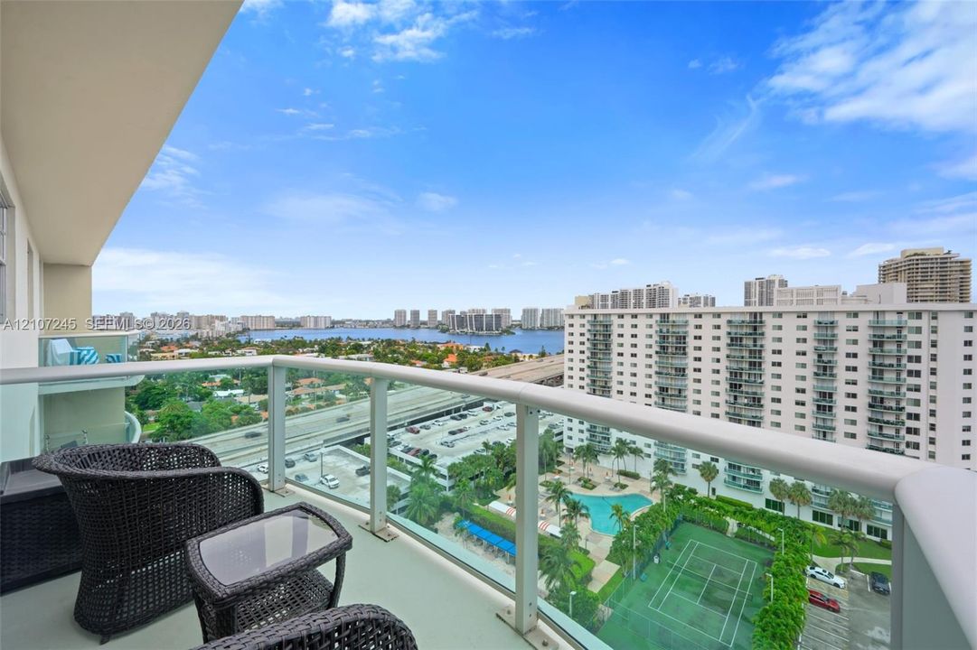 Elevated balcony featuring glass railings and panoramic water and urban scenery