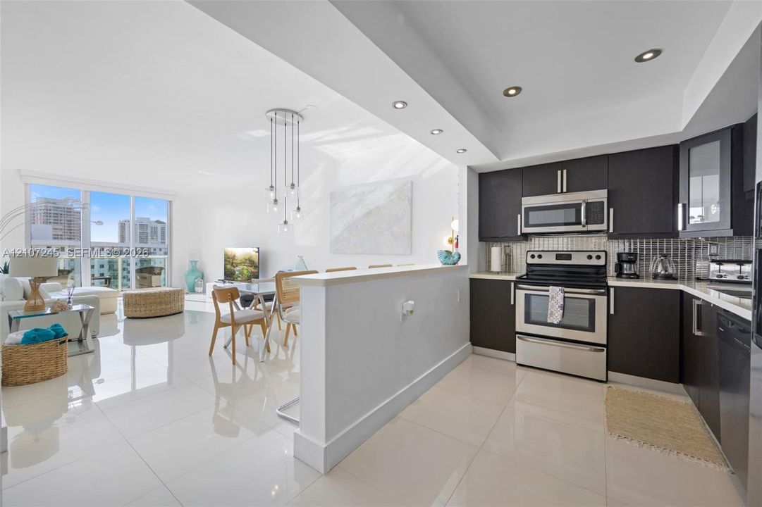 Kitchen featuring dark cabinetry, stainless steel appliances, recessed lighting, and large-format tile flooring