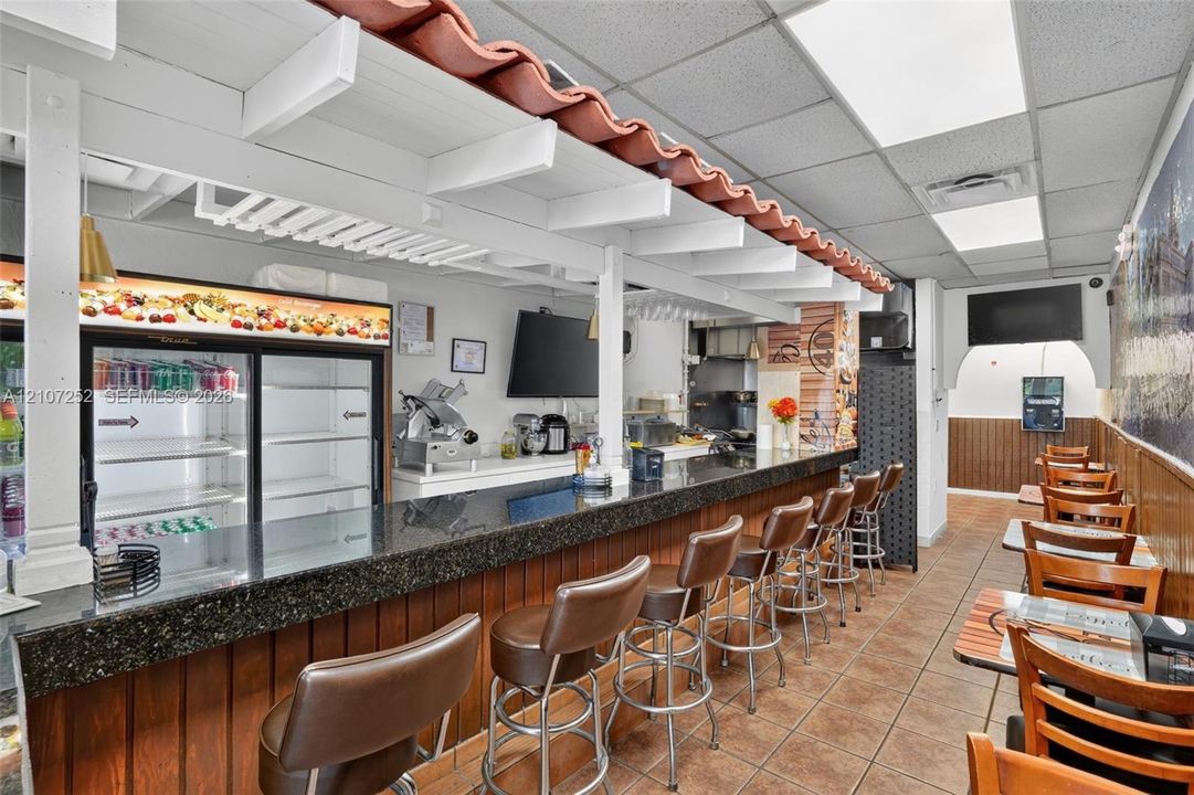 Service area featuring a stone-top counter, wood-paneled base, decorative terracotta tile trim, and recessed drop-ceiling lighting