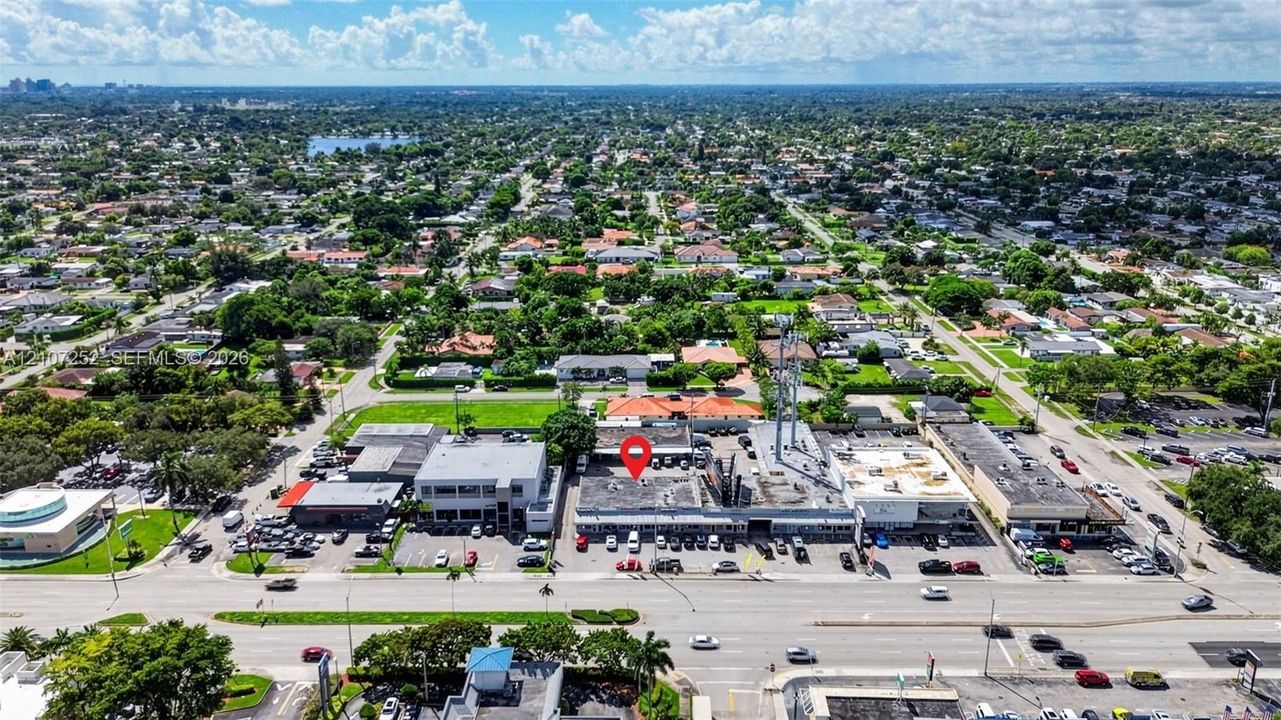 Aerial perspective featuring a commercial structure with direct street frontage, dedicated parking area, and flat roofing system
