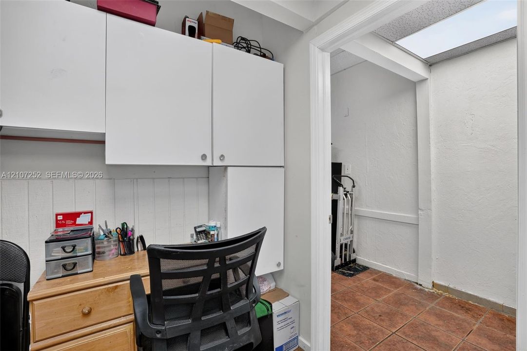 Built-in white cabinetry, paneling details, and terracotta tile flooring