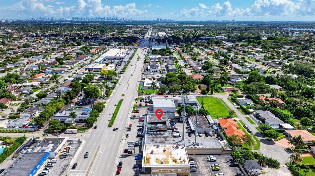 Aerial perspective featuring commercial property with paved surface parking, dual antenna towers, and road frontage on a major thoroughfare