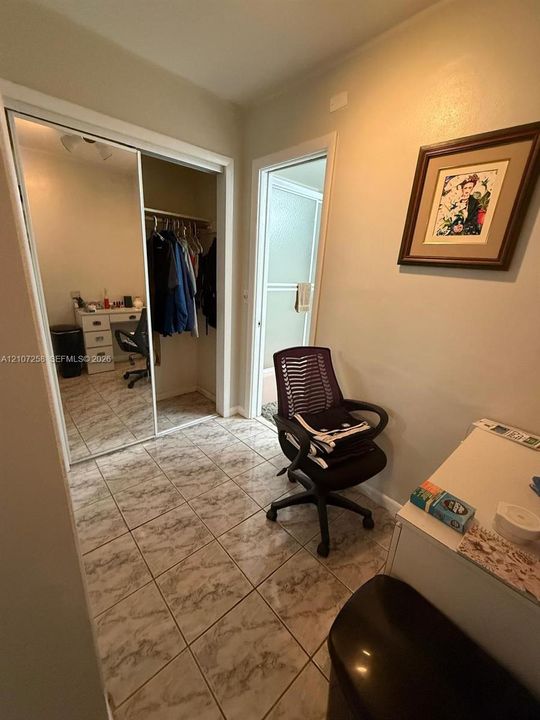 Tiled flooring throughout with sliding mirrored closet doors and built-in closet shelving