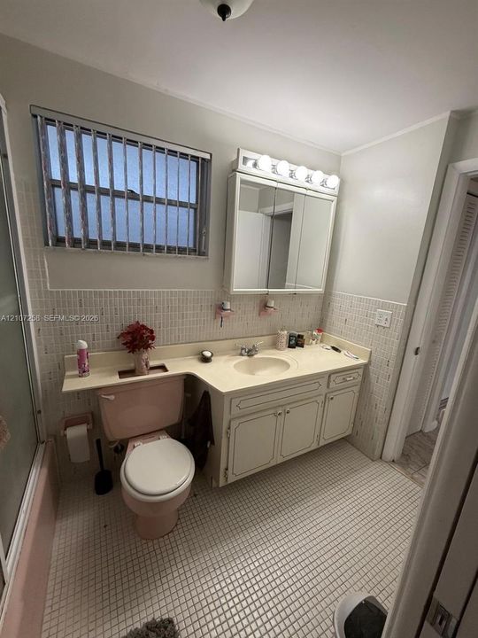 Bathroom featuring a built-in vanity with an integrated countertop and sink, mirrored medicine cabinet, mosaic tile wall accents, and a tiled floor