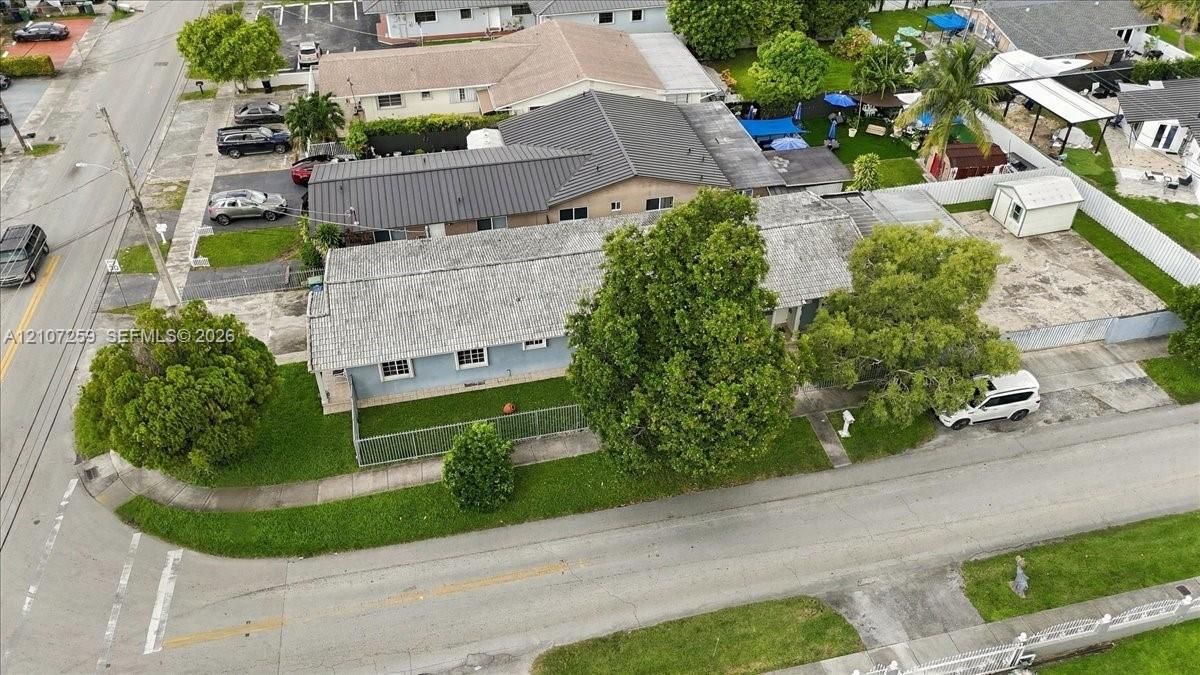 Corner lot property featuring a single-story residence, shingle roofing, paved driveway, and mature landscaping