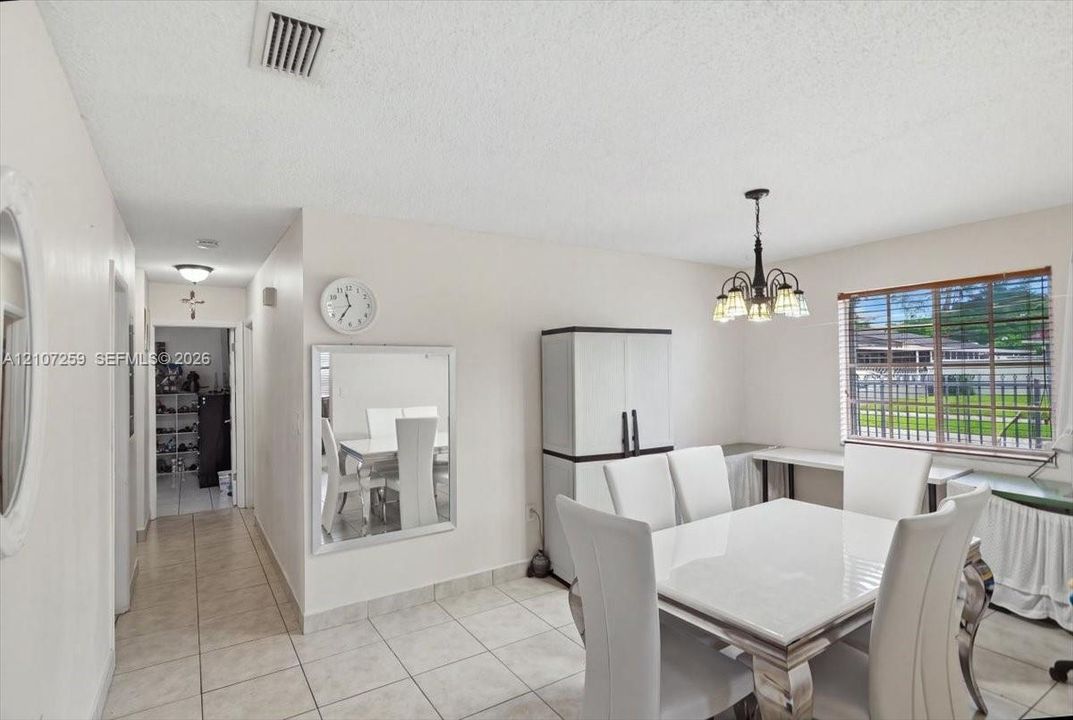 Ceramic tile flooring throughout, multi-light chandelier, and large window with exterior grid detailing
