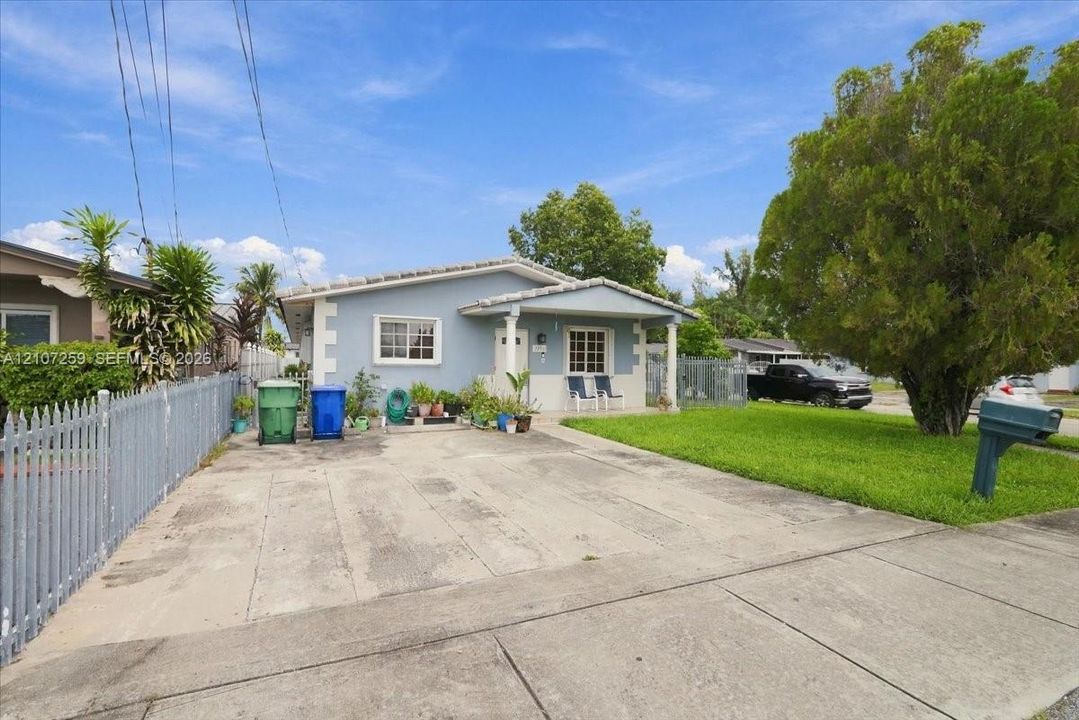 Single-story residence featuring a covered front porch, light blue siding, decorative white corner trim, and a concrete driveway