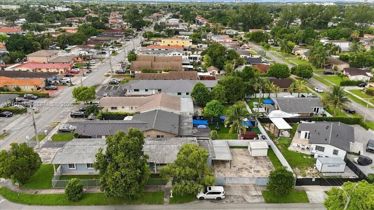 Aerial perspective of a suburban neighborhood featuring paved street access, established mature trees, concrete driveways, and landscaped residential lots