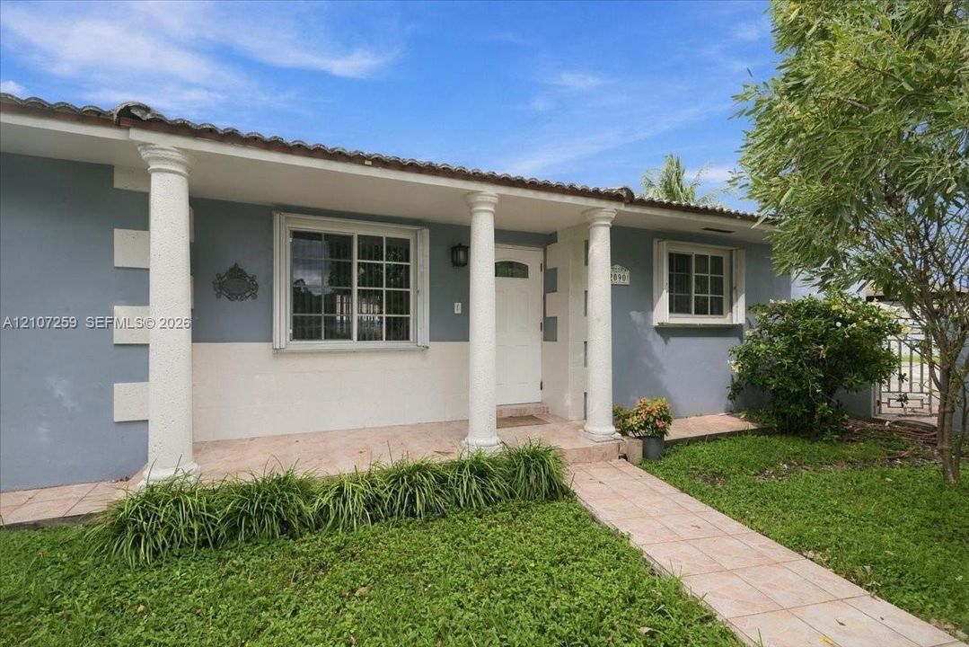 Exterior facade featuring a covered entryway with decorative columns, tiled front porch, light-toned masonry corners, and horizontal window grid detailing