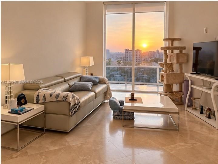 Floor-to-ceiling windows with a sunset cityscape backdrop and stone-finish tile flooring