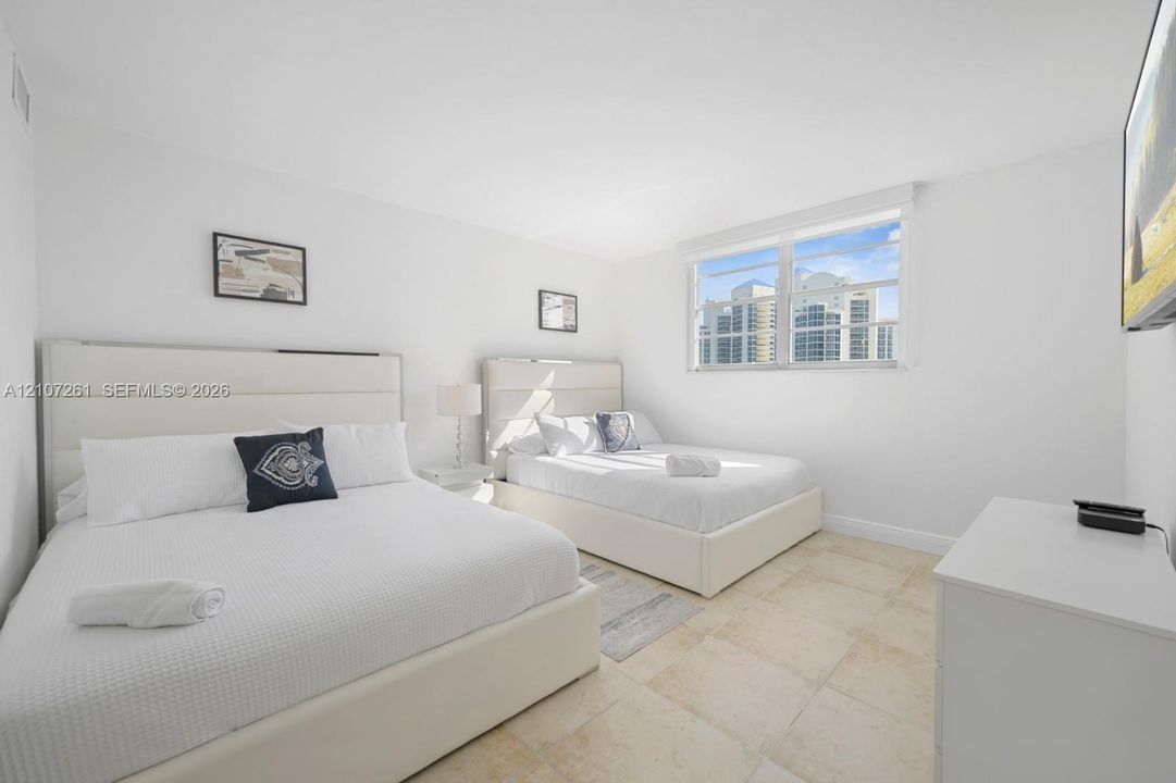 Neutral-toned tile flooring, large multi-pane windows, and minimalist wall finishes