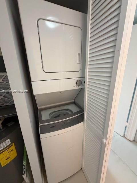 Stacked washer and dryer unit concealed behind white louvered bifold doors