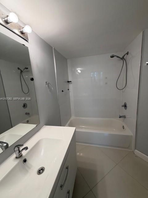 Bathroom featuring a white vanity with an integrated sink, polished chrome faucet, full-height wall-mounted mirror, white tile-surround tub-shower combination, and large-format diagonal floor tiling