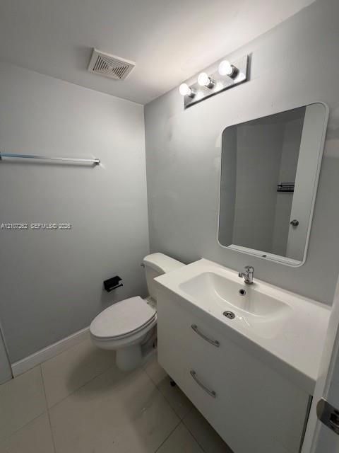 White vanity with integrated sink, rectangular wall-mounted mirror, polished chrome fixtures, and large-format tile flooring
