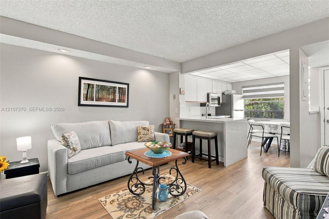 Living area featuring wood-finish flooring, recessed lighting, and a breakfast bar with stone-finish countertops
