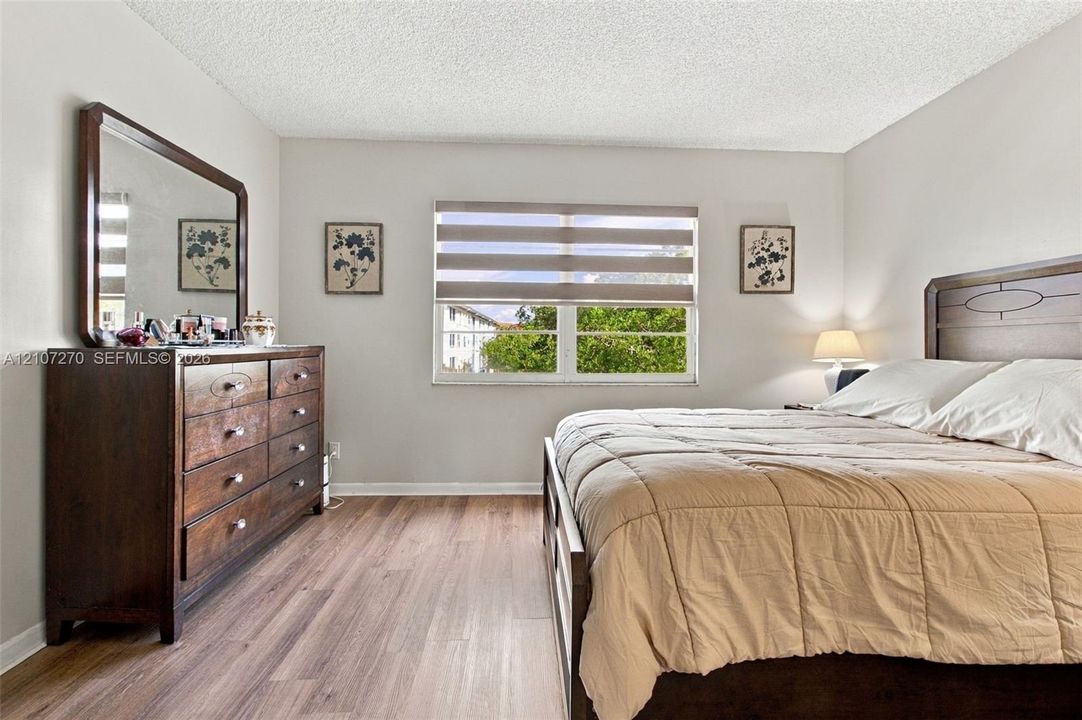 Neutral-toned walls paired with wood-finish flooring and a central window featuring horizontal blinds