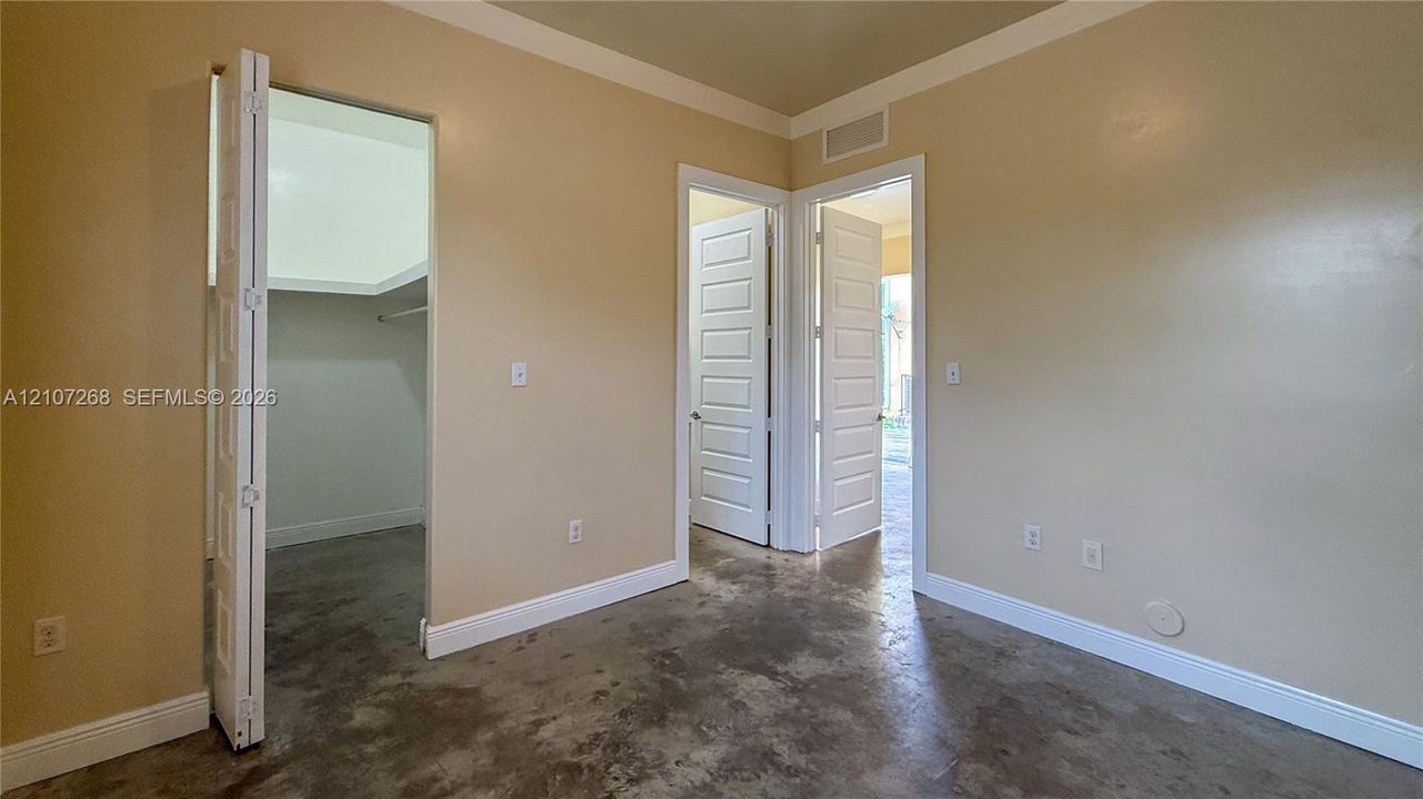 Interior space featuring polished concrete flooring, multi-panel doors, and a walk-in closet with built-in shelving