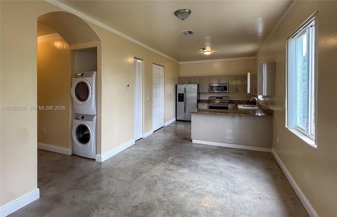 Kitchen featuring a stone countertop, integrated stainless steel appliances, and cabinetry