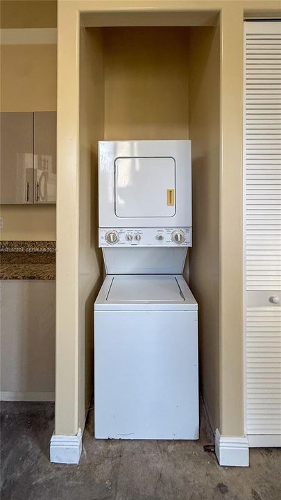Laundry closet featuring a stackable white washer and dryer unit