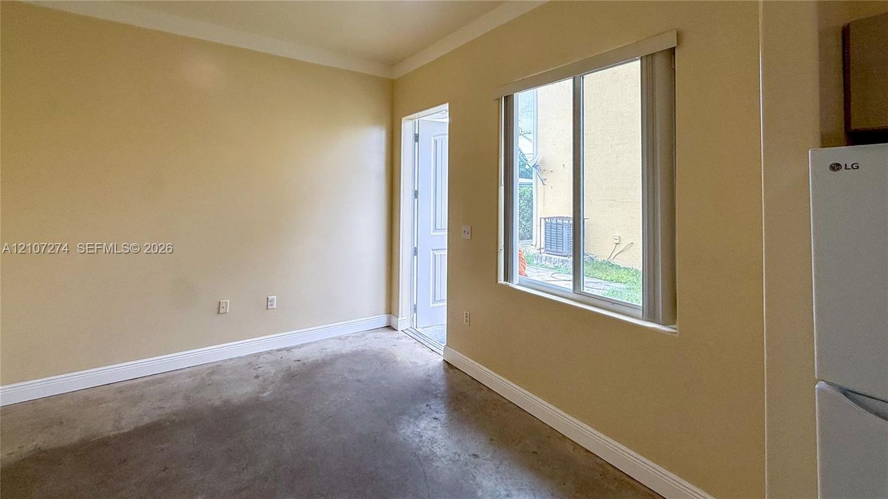 Room featuring concrete flooring, neutral wall tones, a large window, and an exterior door
