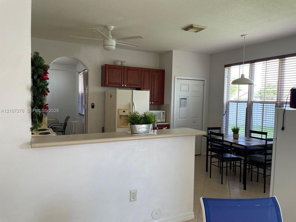 Kitchen featuring a breakfast bar, wood-tone cabinetry, arched doorway, ceramic tile flooring, and pendant lighting