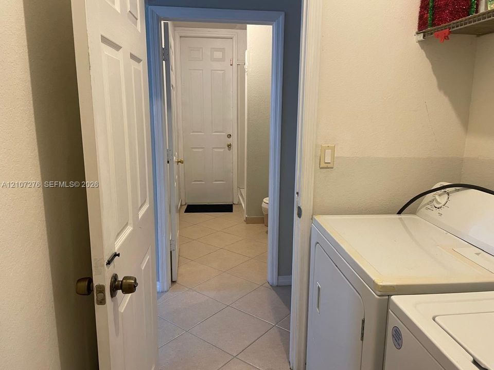 Utility area featuring tiled flooring and a wall-mounted shelving unit