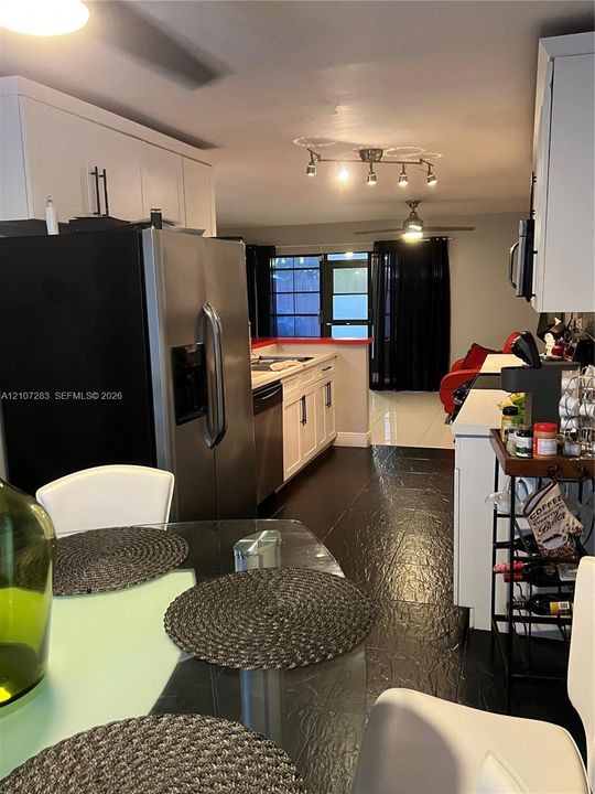 Kitchen featuring white cabinetry, stainless steel appliances, dark tile flooring, track lighting, and a multi-pane glass door