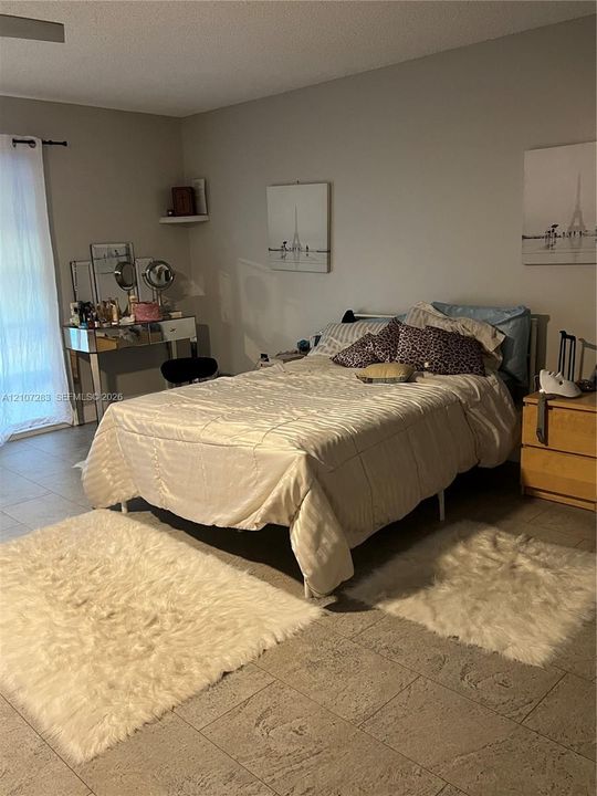 Neutral-toned room featuring large-format ceramic tile flooring, a wall-mounted floating display shelf, and glass sliding door entry