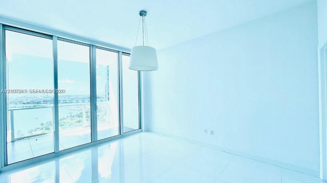 Floor-to-ceiling glass sliding doors, polished tile flooring, pendant lighting, and an expansive balcony