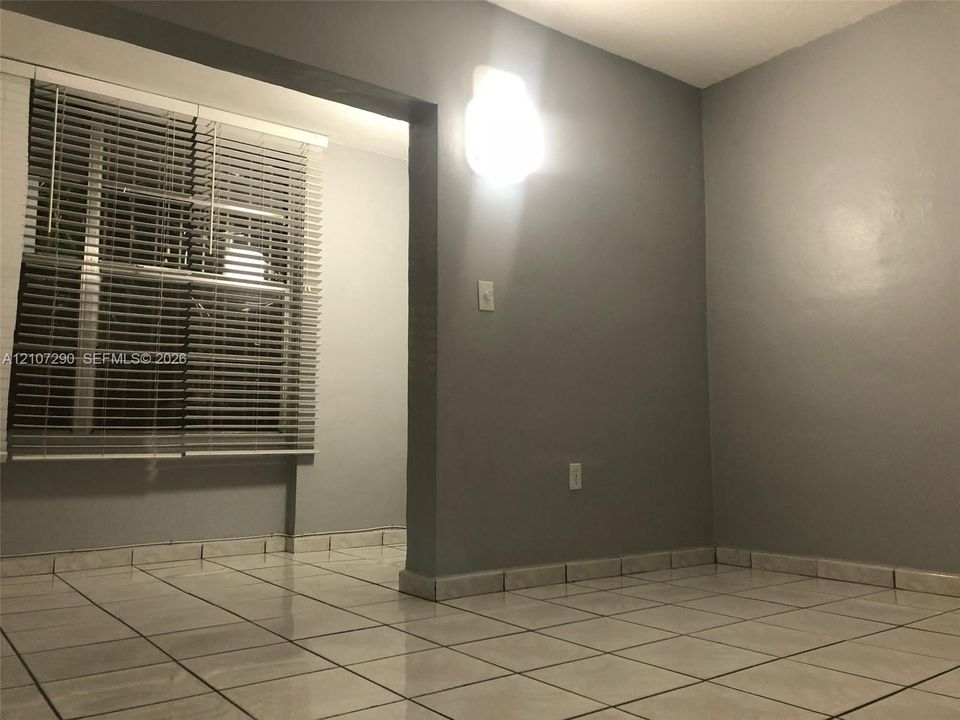 Interior featuring neutral gray wall paint, light-toned ceramic tile flooring, and horizontal window blinds