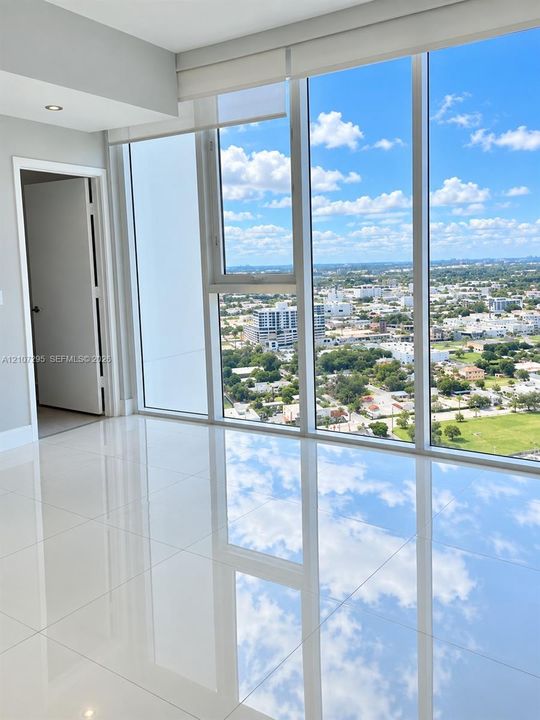 Floor-to-ceiling windows, polished tile flooring, and integrated recessed lighting, accented by expansive urban scenery