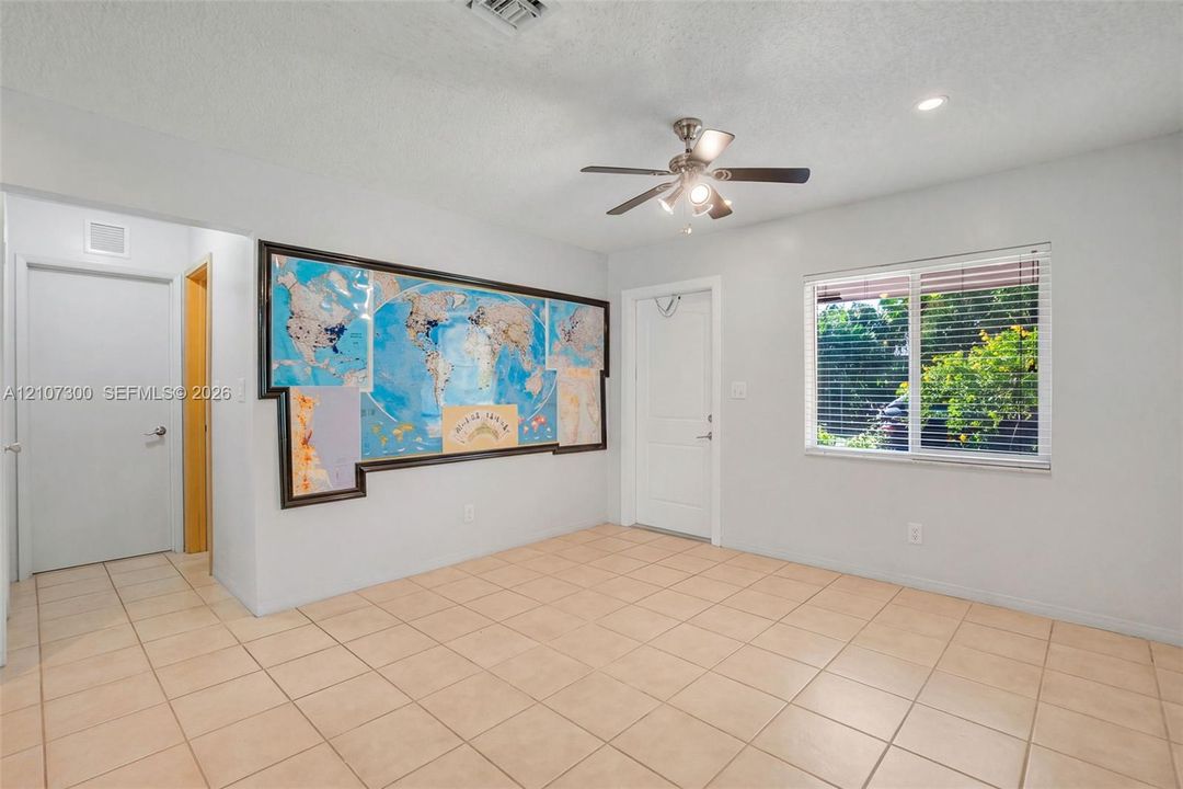 Interior space featuring neutral tile flooring, a multi-blade ceiling fan with integrated lighting, and a horizontal sliding window