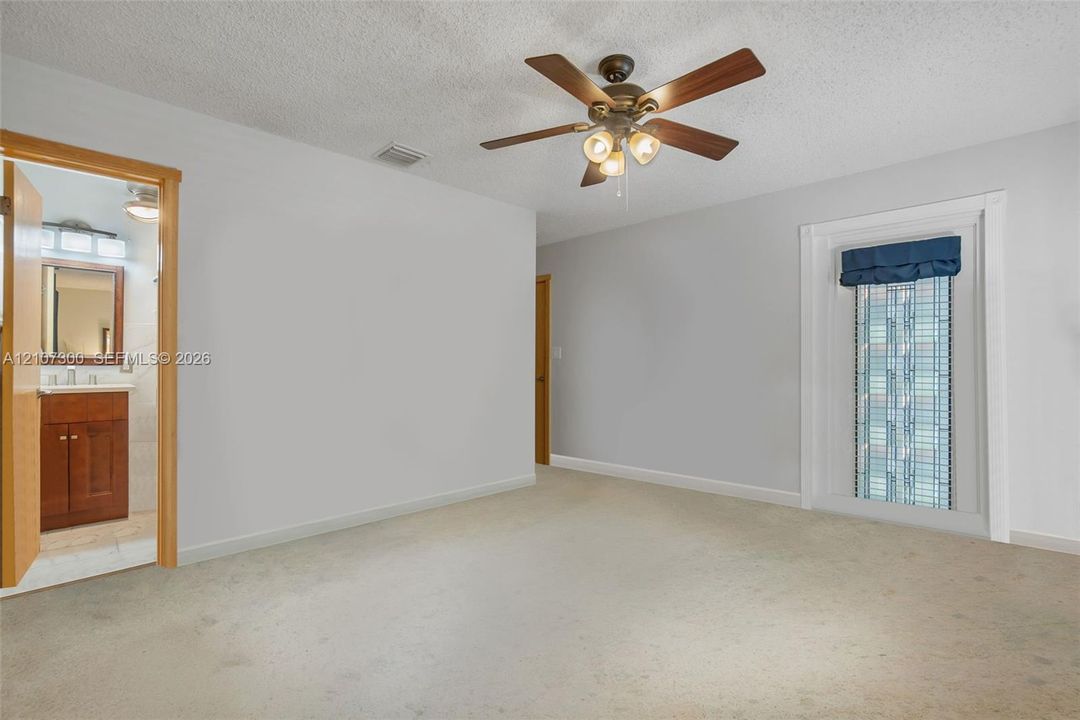 Interior space featuring carpeting, a multi-blade ceiling fan with integrated lighting, and a single-pane window with interior trim