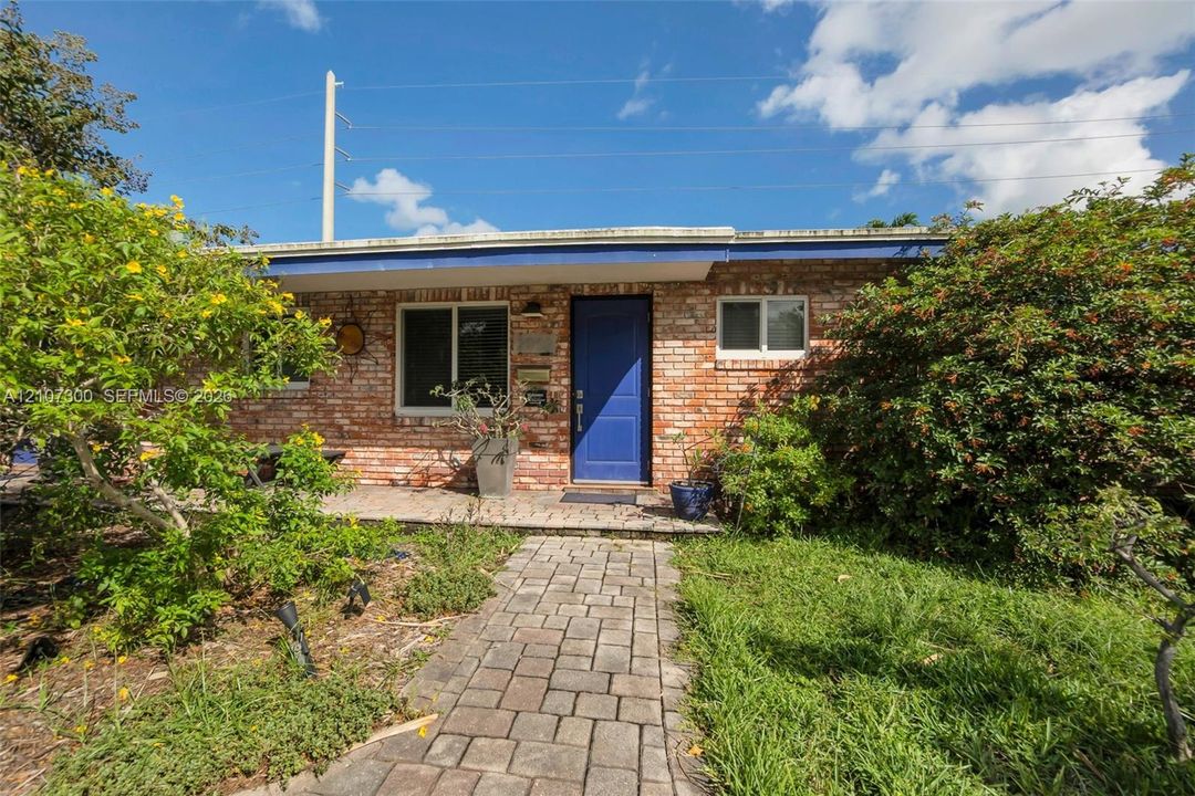 Single-story brick exterior featuring a covered front porch, paver walkway, and blue entry door