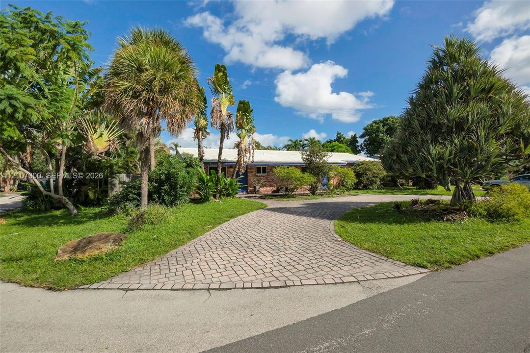Brick exterior, paver driveway, and mature landscaping