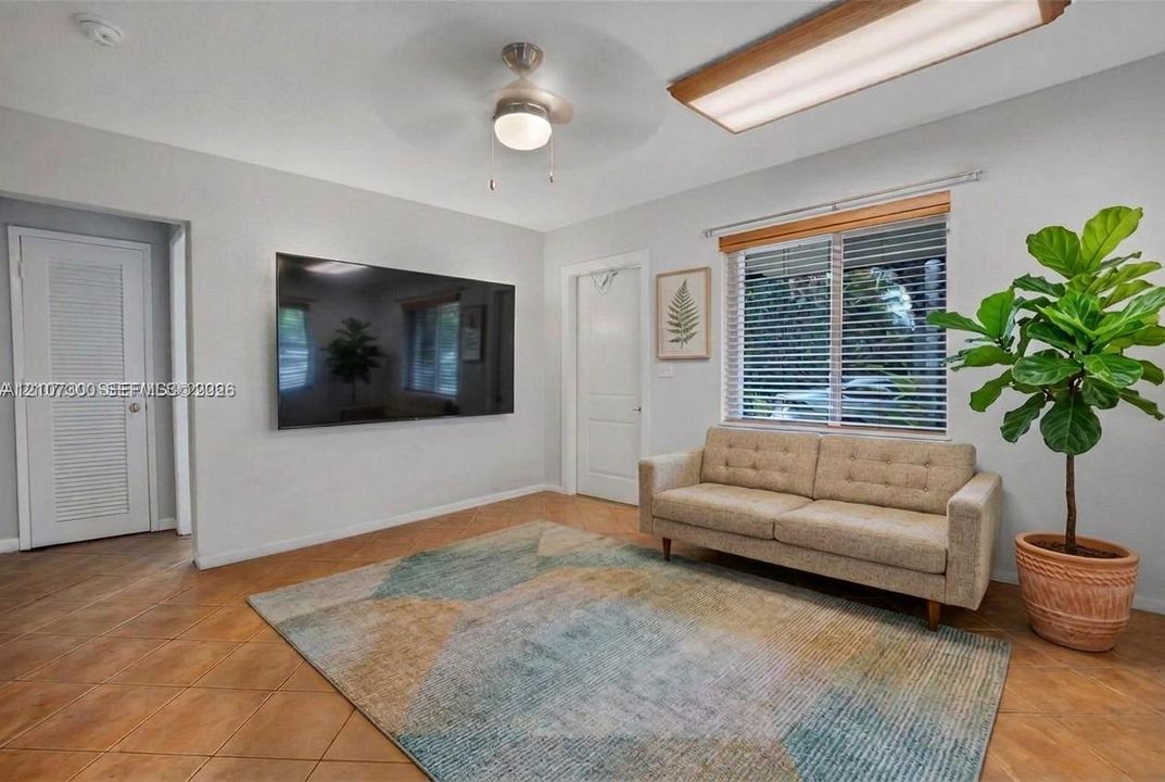 Ceramic tile flooring, neutral wall tones, multi-panel interior doors, window with horizontal blinds, and ceiling fan with integrated lighting