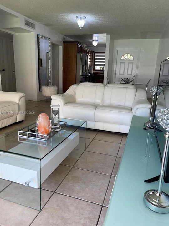 Large-format neutral floor tile, flush-mount crystal-style ceiling lighting, and six-panel exterior entry door