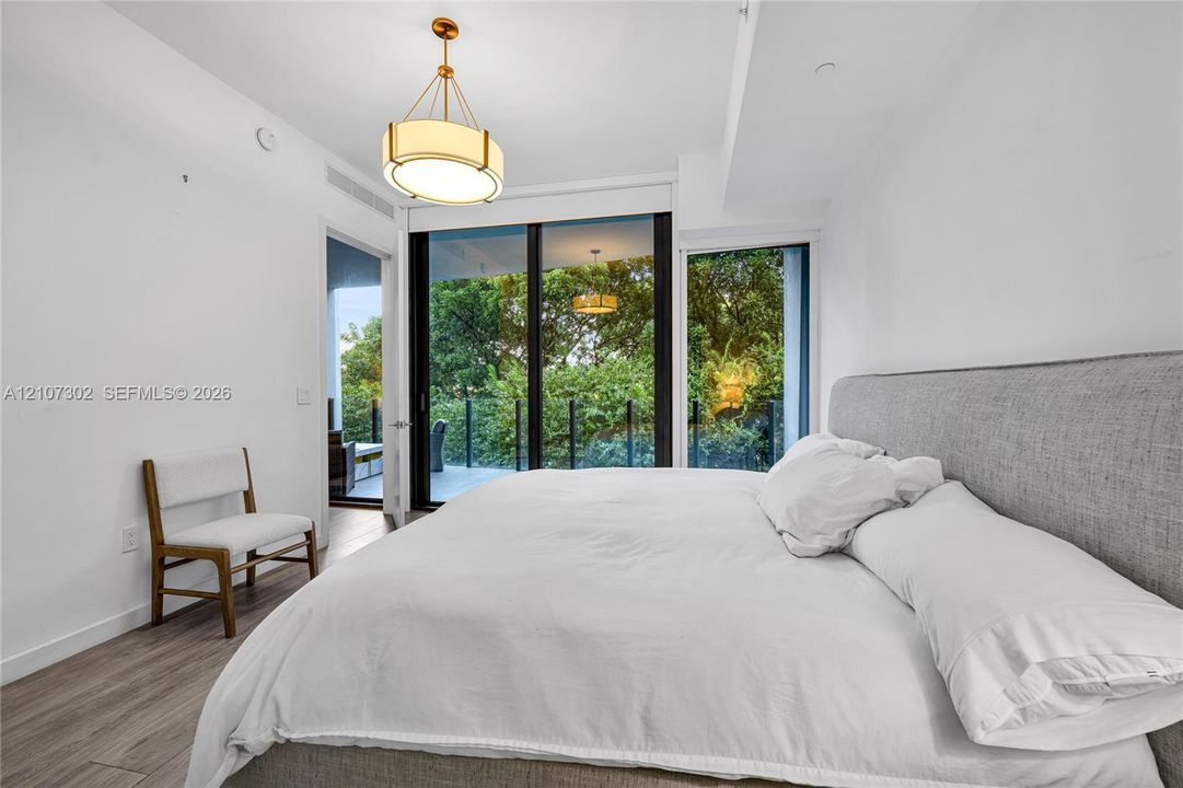Floor-to-ceiling glass sliding doors, wood-finish flooring, recessed lighting, and a modern drum-style pendant light fixture