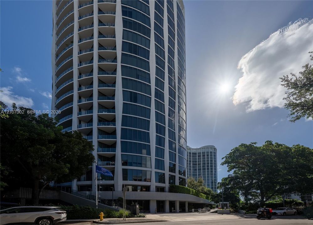 High-rise building exterior featuring a curved facade, floor-to-ceiling glass windows, and wrap-around balconies